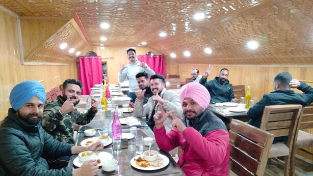 A group of people dining in a room with wooden paneling and a patterned ceiling. - Hotel Mughal India (Gund)