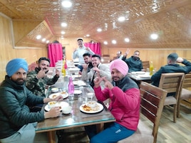 A group of people dining in a room with wooden paneling and a patterned ceiling.