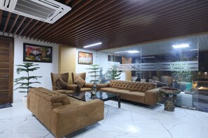 A modern interior with a sofa set, a glass partition, and a decorative fountain. - Sky Suites (Gurugram)