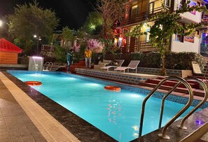 A swimming pool with a tiled edge, a metal pool ladder, and a few lounge chairs.