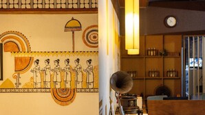 Quarto com um mural, um relógio e uma estante com garrafas.