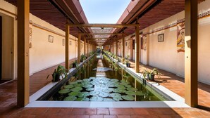 Um corredor com um elemento central de água, plantas em vasos e elementos arquitetônicos tradicionais.
