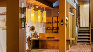 Um espaço de bar acolhedor, com luminárias pendentes, prateleiras com garrafas, um balcão de madeira e uma escadaria.