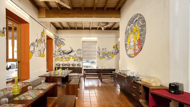 Um restaurante com bancos de madeira, piso de azulejos e um mural na parede.
