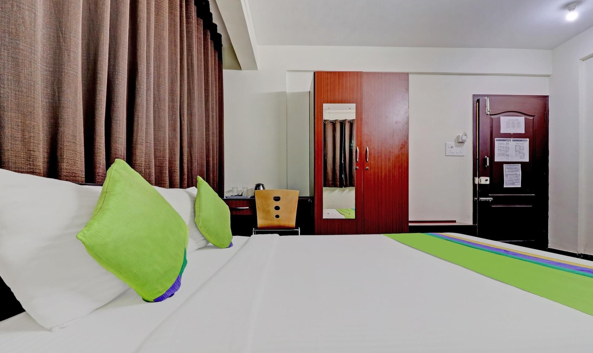 Une chambre d’hôtel avec un lit, un bureau, une chaise, une armoire et une porte.