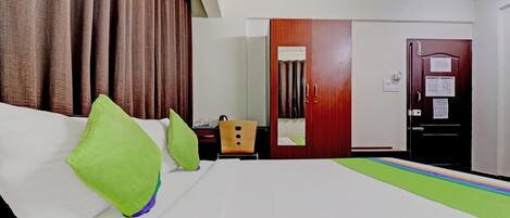 Une chambre d’hôtel avec un lit, un bureau, une chaise, une armoire et une porte.