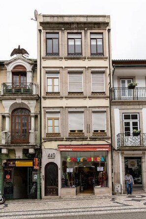 A multi-story building with a ground-level shop, a balcony on the second floor, and a satellite dish on the roof. - Your Opo Capela Apartments (Porto)