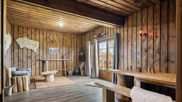 A rustic cabin interior with wooden walls, a sofa, a table, and a bench. - Gîtes de France® - Hygge (SAUMONT LA POTERIE)