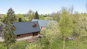 A rustic cabin with a sloped roof, surrounded by lush greenery and trees. - Gîtes de France® - Hygge (SAUMONT LA POTERIE)