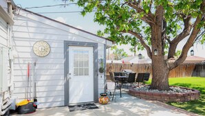 Et hus med garageport, et træ, en terrasse med bord og stole, og et ur på væggen.