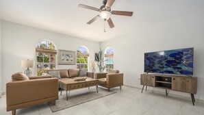 Un soggiorno con ventilatore a soffitto, televisore e tavolino.