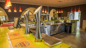 A bar area with multiple taps, a counter with bottles, and a view of the outside through a window. - Damara Mopane Lodge (Khorixas)