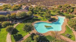 Vista aérea de una zona residencial con piscina, casas y zonas verdes.
