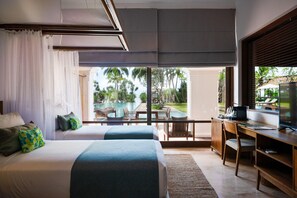 A bedroom with a large bed, a desk, and a view of a pool and palm trees. - Kayaam House (Rekawa)