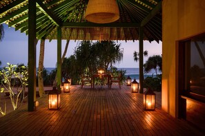 A wooden deck with a pergola and lanterns, overlooking the ocean. - Kayaam House (Rekawa)