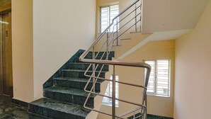 A staircase with metal railings, a landing, and a window with blinds. - Collection O 81451 Capital Casa (Barasat)