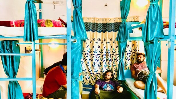Quarto com beliches, cortinas verde-água e padrão decorativo.