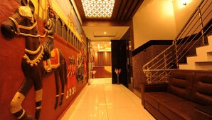 A hotel lobby with a staircase, a wall-mounted horse statue, and a reception area. - Mc Suites Mysuru (Mysore)