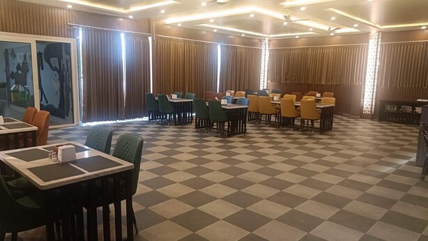 A hotel dining area with checkered flooring, multiple tables, and chairs. - Mc Suites Mysuru (Mysore)