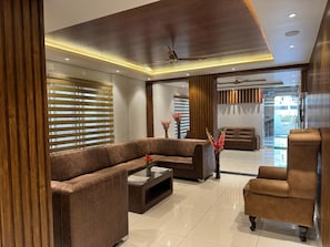 A modern living room with a sectional sofa, a coffee table, and a side chair. - Mc Suites Mysuru (Mysore)