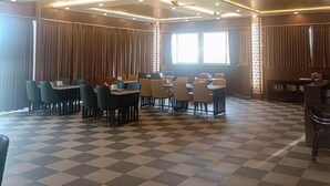A dining area with checkered flooring, ceiling fans, and recessed lighting. - Mc Suites Mysuru (Mysore)