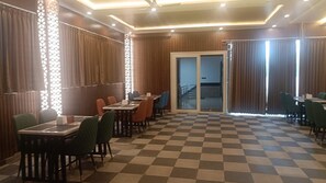 A hotel room with a checkered floor, wooden paneling, and a sliding glass door leading to a balcony. - Mc Suites Mysuru (Mysore)