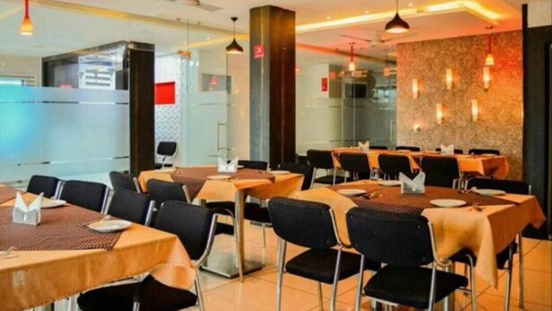Restaurante com mesas postas para refeições, cadeiras e iluminação pendente.