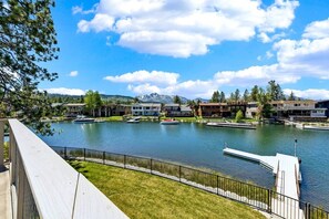 Vista para um lago com edifícios modernos, um píer e céu limpo.