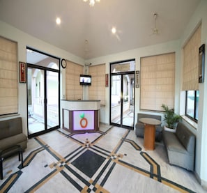 A lobby with a reception desk, seating areas, a clock, and a television. - Angel Resort Amusement Water Park (Jalsu)