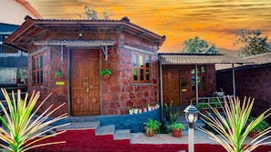 A small brick house with a red door, a window, and a small porch area. - Saveda Farm Cottages By Spicy Mango (Karjat)