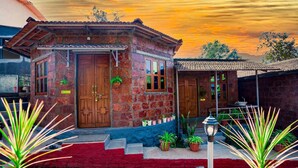 A small brick house with a red door, a window, and a small porch area. - Saveda Farm Cottages By Spicy Mango (Karjat)