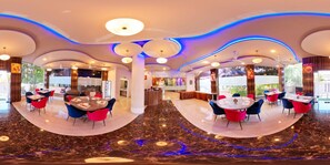 A modern hotel lobby with round tables and chairs, a reception desk, and a view of the outdoors. - Hotel Sai Dharam Palace (Rahata)