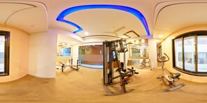 A panoramic view of a modern gym with various exercise equipment, large windows, and a curved ceiling design. - Hotel Sai Dharam Palace (Rahata)