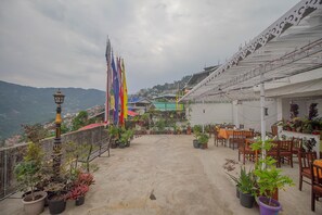 A rooftop terrace with potted plants, outdoor seating, and flags. - Palri Boutique Hotel (Gangtok)
