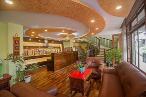 A lobby with a reception desk, seating area, staircase, and potted plants. - Palri Boutique Hotel (Gangtok)