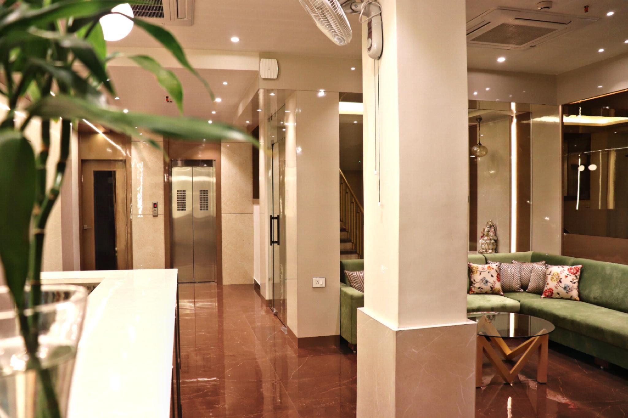 A hotel lobby with a green sofa, a glass table, and a plant.
