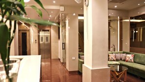 A hotel lobby with a green sofa, a glass table, and a plant. - Hotel Rion (Udaipur)