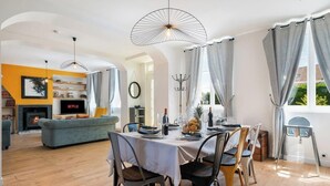 A modern living room with a fireplace, sofa, dining table, and a TV displaying 'NETFLIX'. - Gîtes de France® - L'Orée D'Etretat (LA POTERIE CAP D'ANTIFER)