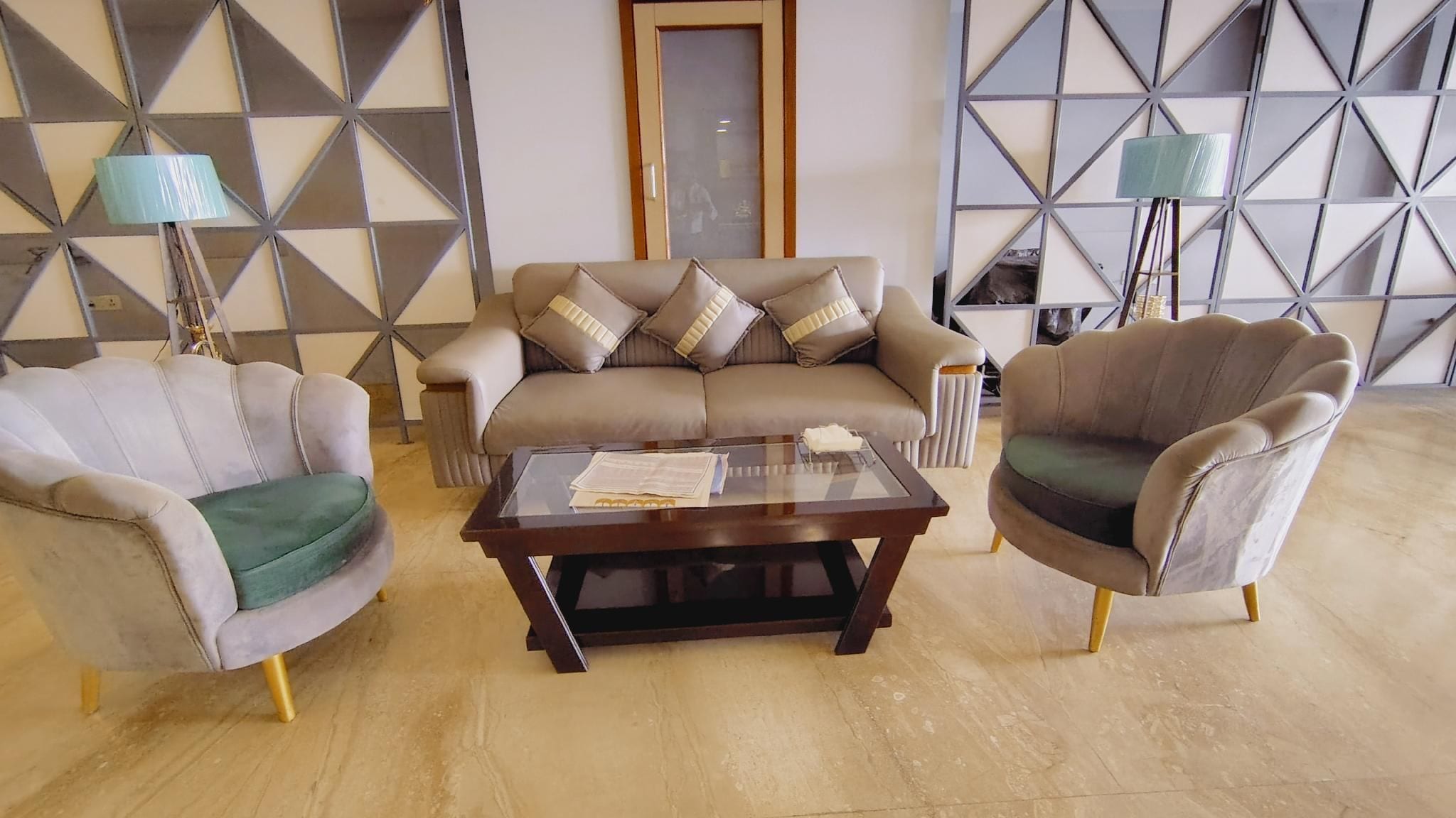 A living room with a sofa, two armchairs, a coffee table, and a patterned wall.