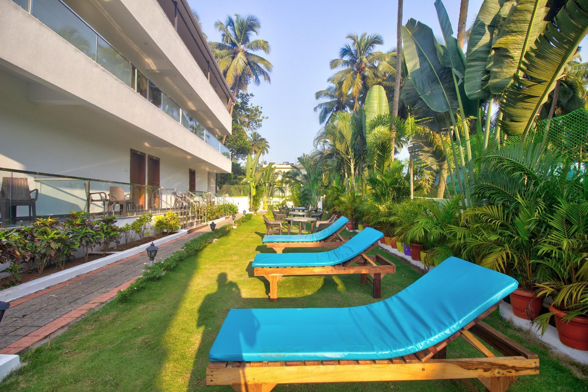 A resort with outdoor lounge chairs, a pool area, and lush tropical vegetation.