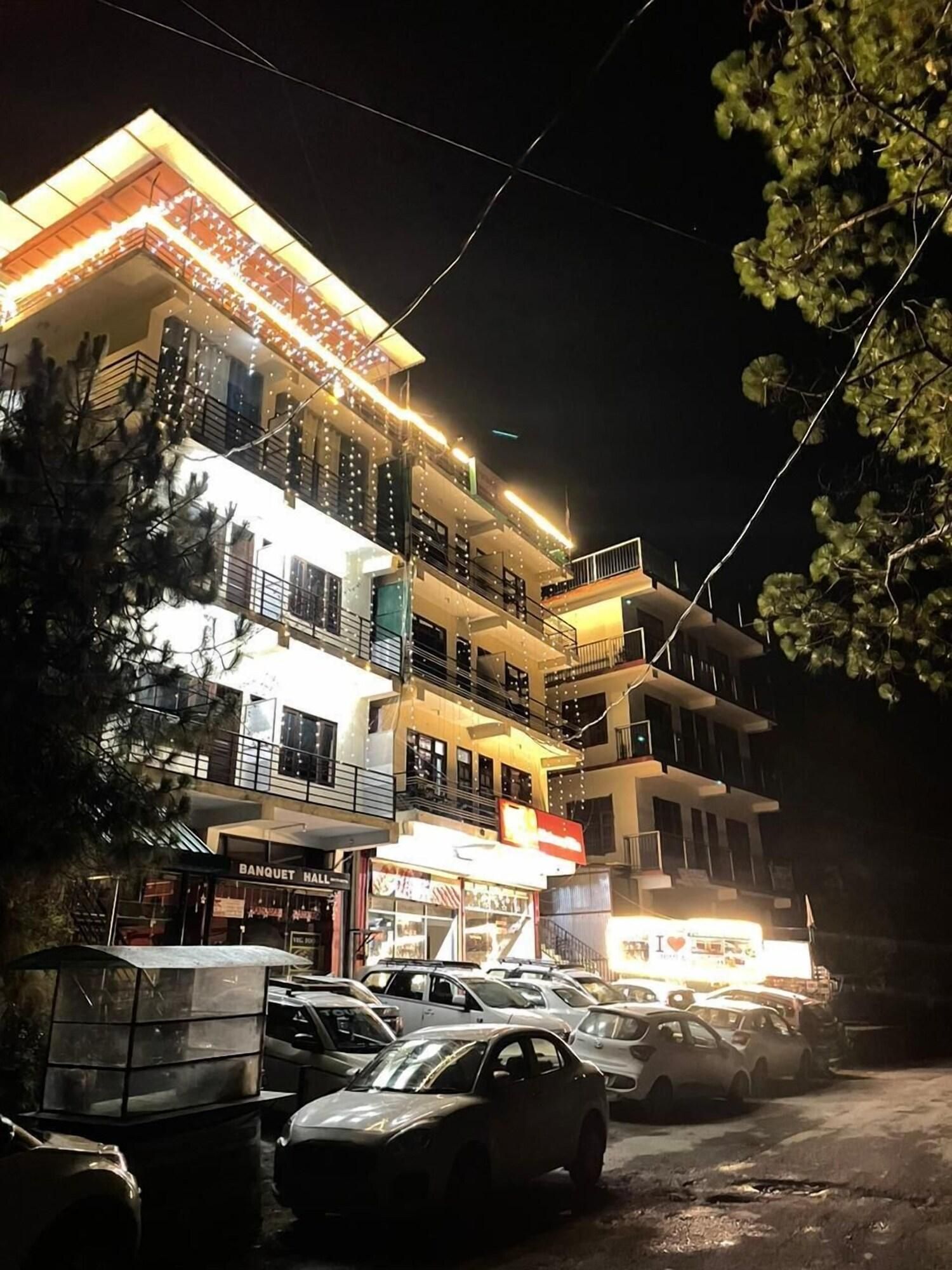 A multi-story hotel with balconies, a visible restaurant, and a parking lot with cars.