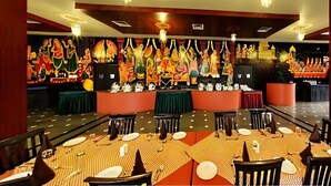 A restaurant with a long table, chairs, and a decorative wall with statues. - The Udai Bagh (Māvli)