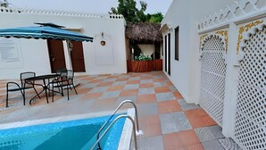 A pool area with a checkered floor, a poolside table, and a covered seating area. - The Udai Bagh (Māvli)