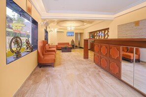 A hotel lobby with a reception desk, seating area, and a large mirror. - Hotel Green One Earth (Yamkeshwar)
