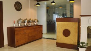 Una zona de recepción con un mostrador de madera, un reloj y una puerta de vidrio que da a una cocina.