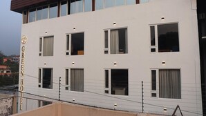 Un hotel con fachada blanca, numerosas ventanas y un cartel con su nombre.