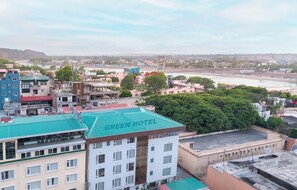 A hotel with a green roof, multiple floors, and a view of a river and cityscape. - Hotel Green One Earth (Yamkeshwar)