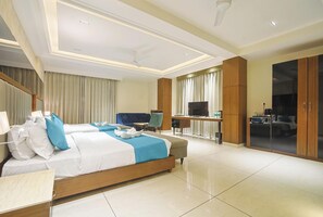 A hotel room with a large bed, a desk, a television, and a wardrobe. - Hotel Green One Earth (Yamkeshwar)