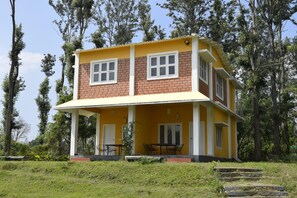 A two-story yellow building with a covered porch and a table and chairs set outside. - River Valley Resort Masinagudi (Ootacamund)