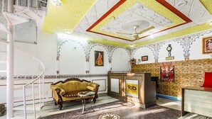 Un vestíbulo de hotel con suelo de mármol, un mostrador de recepción, un sofá y una escalera.